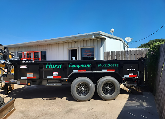 A black trailer with green lettering parked in front of a building.