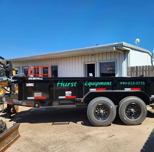 Black equipment trailer parked outside building.